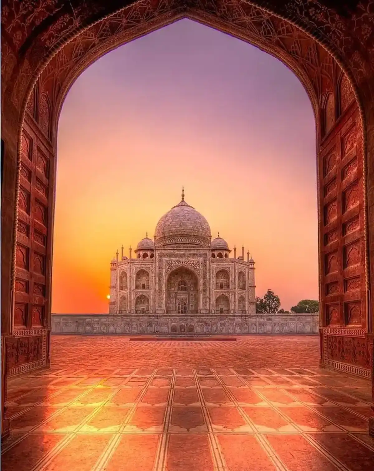 Taj Mahal at sunrise, viewed through a Mughal gateway